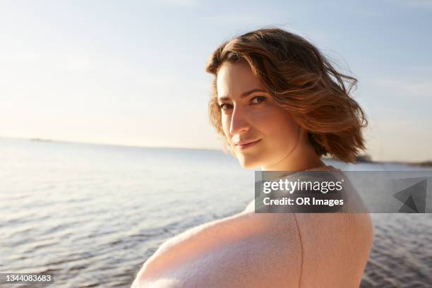 portrait of blond woman at the beach - woman looking over shoulder serious stock pictures, royalty-free photos & images