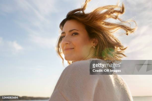 portrait of smiling woman with tousled hair at sunset - autoconfiança - fotografias e filmes do acervo