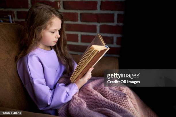 girl sitting in armchair at home reading book - children room wall stock pictures, royalty-free photos & images