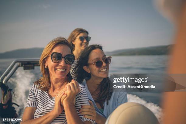 mother and daughters relax on motorboat at sunrise - watervaartuig stockfoto's en -beelden