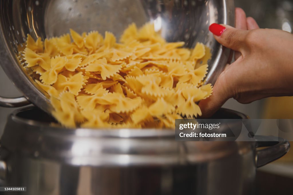 Pouring pasta into a pot with boiling water