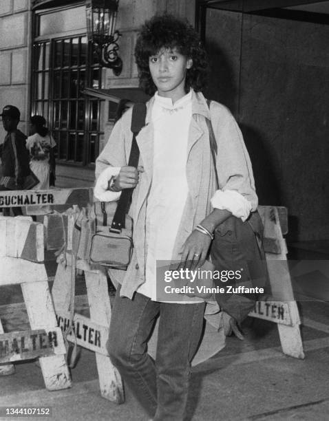 American actress Jennifer Beals carrying a shoulder bag and a camera bag as she passes wooden trestle barriers as she walks in New York City, New...