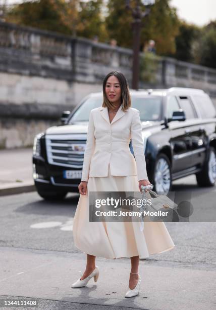 Aimee Song wearing a white blazer and skirt, a white dior bag and white heels on September 28, 2021 in Paris, France.