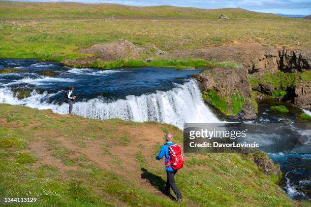 tourists walking and enjoying rejkjafoss waterfall, north iceland. - skagafjordur stock pictures, royalty-free photos & images