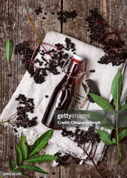 delicious homemade black elderberry liqueur in a glass bottle. - syrup stock pictures, royalty-free photos & images