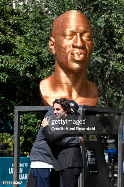 Artist Chris Carnabuci and Terrence Floyd embrace in front of the "Floyd" sculpture during the Confront Art’s First Exhibition launch SEEINJUSTICE in...