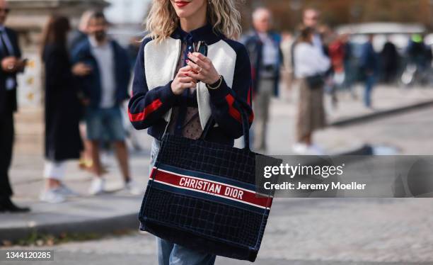 Fashion Week Guest wearing a dior jacket, a transparent blouse, a blue jeans and a dior bag outside Dior on September 28, 2021 in Paris, France.