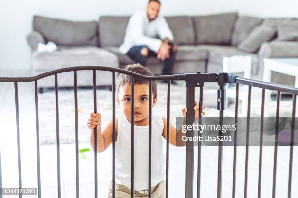 toddler boy trapped in the living room by a baby gate for safety at home - baby gate stock pictures, royalty-free photos & images