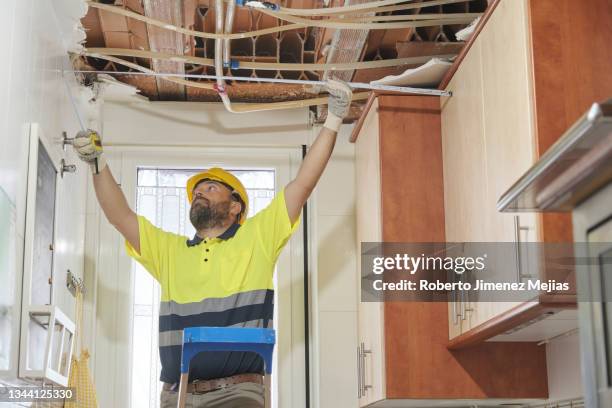 construction worker inspecting a new project. taking measurements and climbing a ladder. - leaking ceiling stock pictures, royalty-free photos & images
