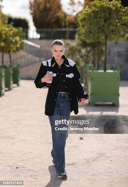 Fashion Week Guest wearing a black jacket, black top and blue jeans outside Dior on September 28, 2021 in Paris, France.