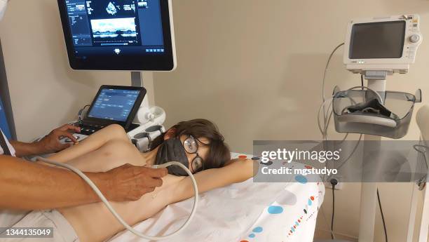 arzt, der das herz eines kinderpatienten mit einem ultraschallgerät untersucht. - echokardiogramm stock-fotos und bilder