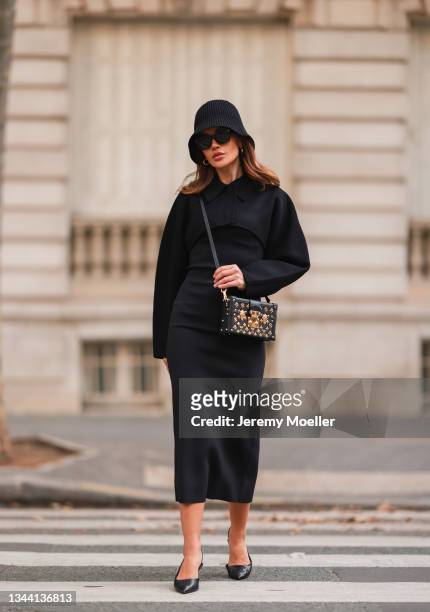 Füsun Lindner wearing black bucket hat, black midi dress, black and gold Louis Vuitton bag, black shades and black slingback heels on September 28,...