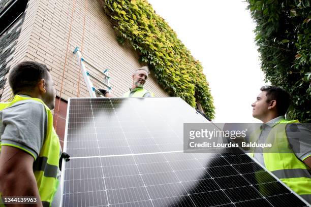 construction worker installing solar panels - green economy stock-fotos und bilder