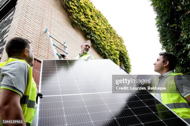 construction worker installing solar panels - economia verde imagens e fotografias de stock