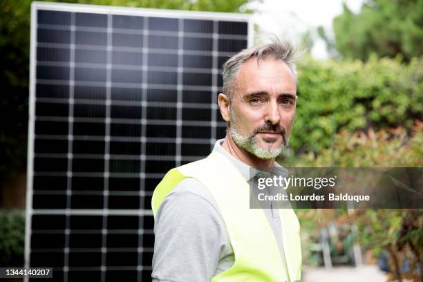 construction worker installing solar panels looking at camera - panel fotografías e imágenes de stock