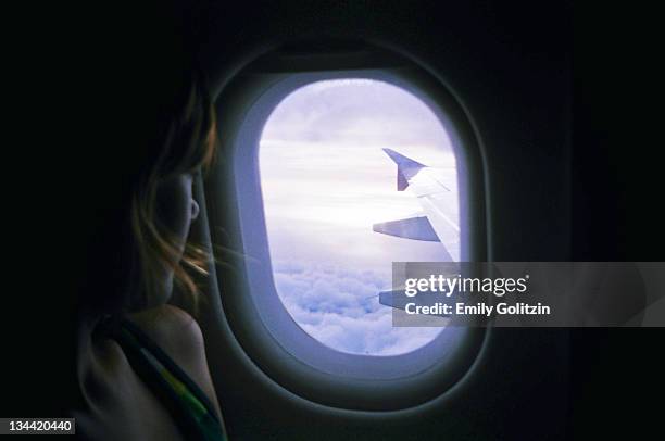 girl looking out airplane window - flugzeugsitz stock-fotos und bilder