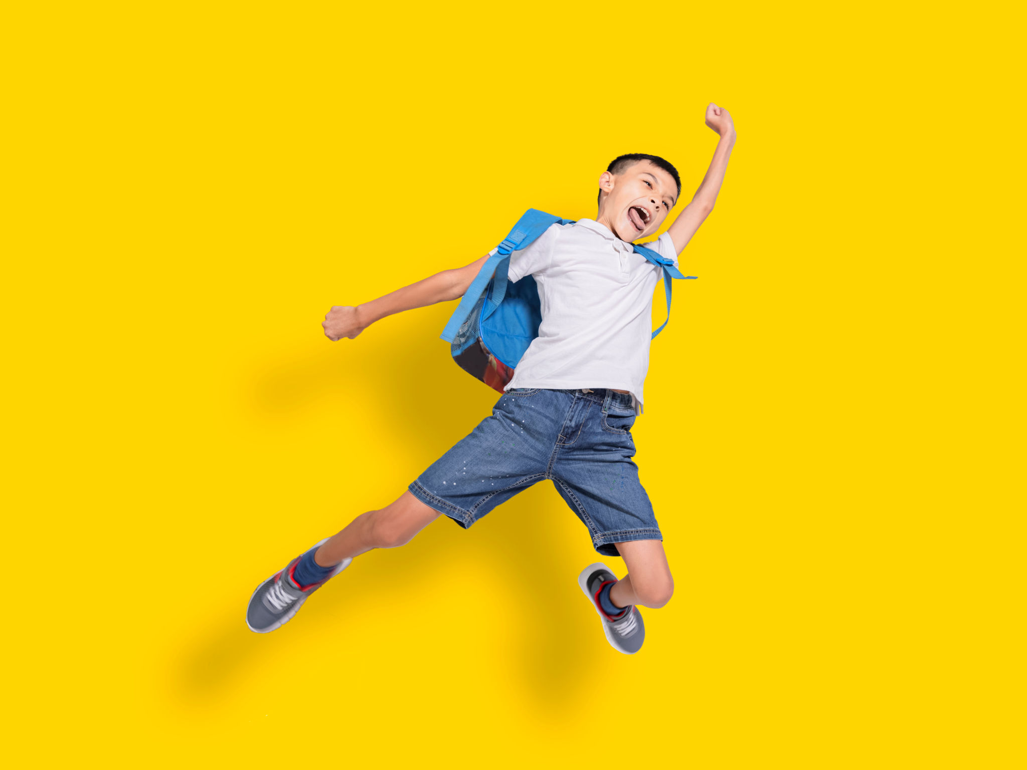 Happy student boy jumping.Isolated on yellow background. Happy student boy jumping.Isolated on yellow background.