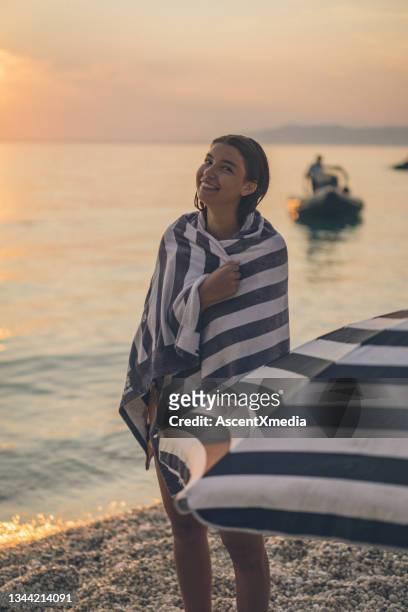 young woman walks down beach at sunrise - striped towel stock pictures, royalty-free photos & images
