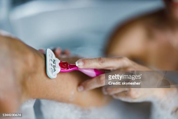 close up of unrecognizable woman shaving her leg. - scheermes stockfoto's en -beelden