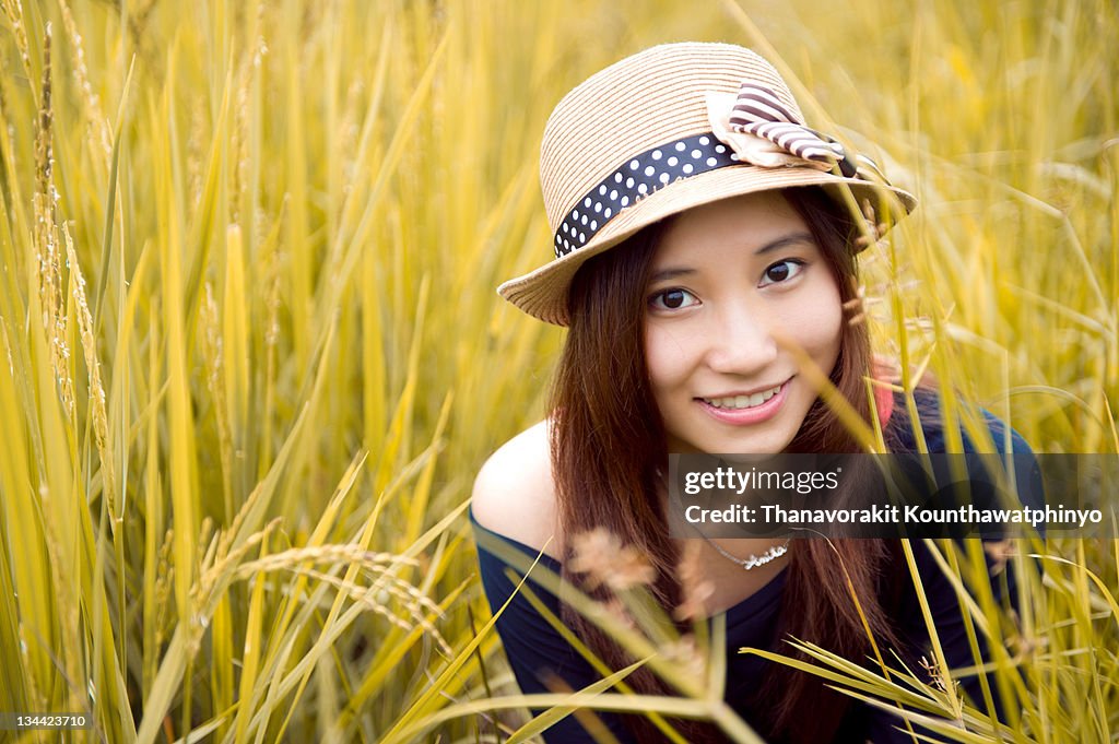 Woman wearing hat sitting in rice field