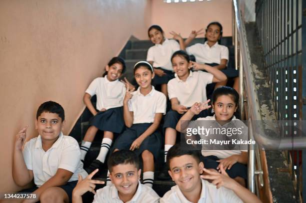 group photo of smiling school children sitting on school staircase - groepsfoto 6 personen stockfoto's en -beelden