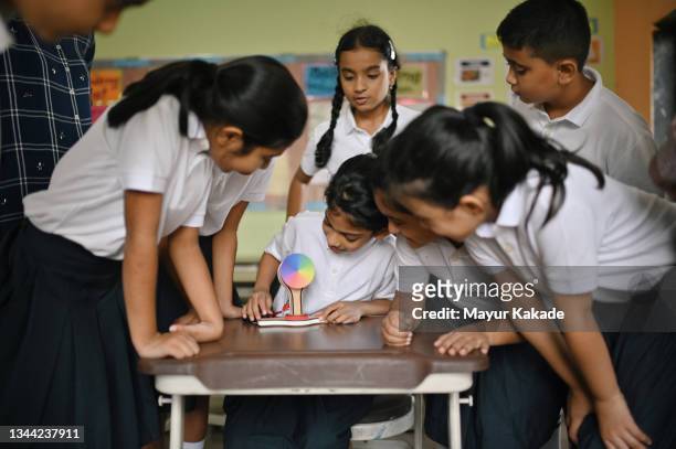 school girl showing science experiment to her classmates in school classroom - school students science stock pictures, royalty-free photos & images