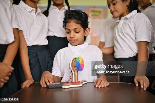 school girl showing science experiment to her classmates in school classroom - school science project stock pictures, royalty-free photos & images
