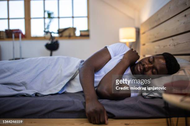 junger mann, der morgens zu hause im bett schläft - lying on side stock-fotos und bilder