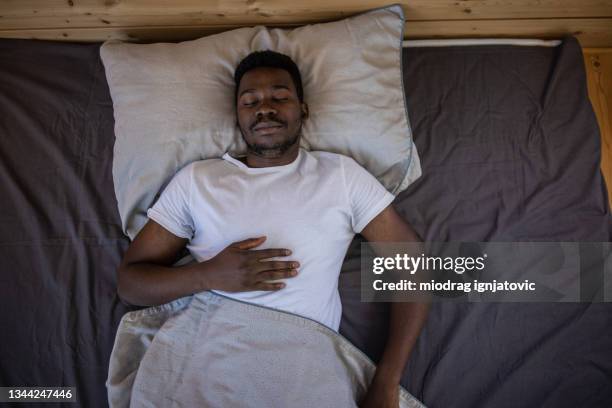 young man sleeping in bed at home - man sleeping on bed stock pictures, royalty-free photos & images