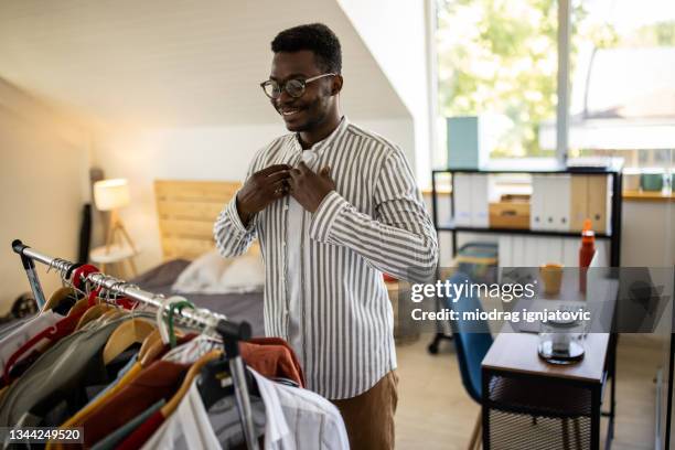 young man dressing up his shirt in bedroom - knäppa knappar bildbanksfoton och bilder