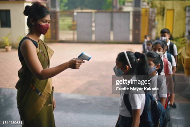 school teacher checks temperature of students at school entrance - covid 19 mask stock pictures, royalty-free photos & images