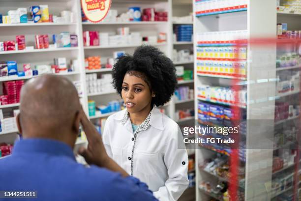 giovane farmacista che aiuta un uomo anziano con mal di testa in farmacia - shopping male foto e immagini stock