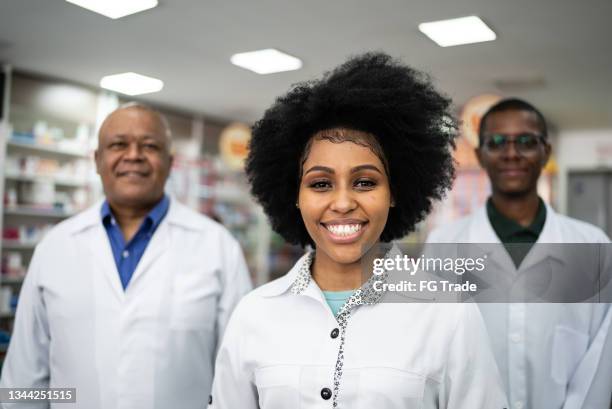 portrait of a young pharmacist with her colleagues at the pharmacy - black pharmacist stock pictures, royalty-free photos & images