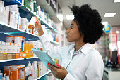 Young pharmacist checking the shelves with a digital tablet at the pharmacy