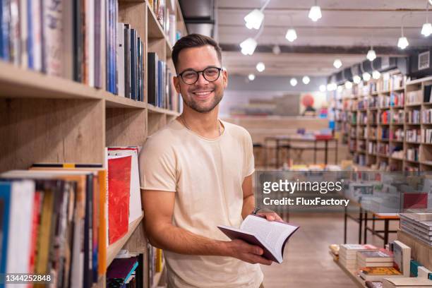 portrait of dedicated male student, searching for a literature at the book store - literature stock pictures, royalty-free photos & images