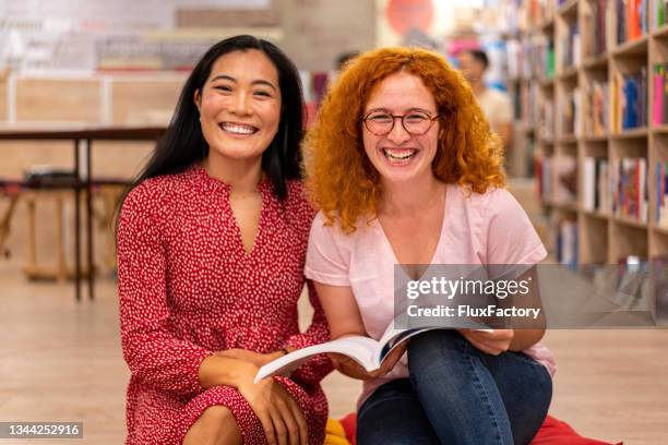 porträt einer selbstbewussten und fröhlichen multirassischen studentin, die gemeinsam in der bibliothek studiert - buchhändler stock-fotos und bilder