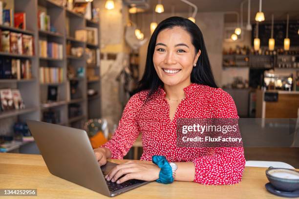 modern young woman of asian ethnicity, e-learning via laptop, at the modern and cozy cafeteria - online learning 個照片及圖片檔