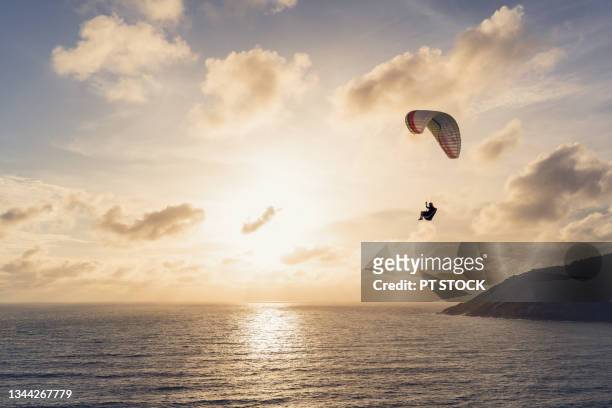 man paragliding overlooking the sea, mountains and sunset. - hang parachute stock-fotos und bilder
