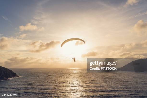 man paragliding overlooking the sea, mountains and sunset. - water glide stock pictures, royalty-free photos & images