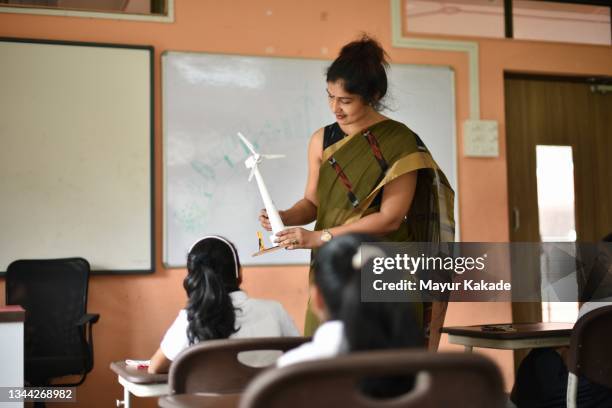 teacher teaching concepts of windmill in the classroom to students - indian male model stockfoto's en -beelden