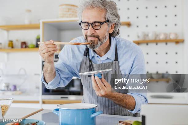 自宅で食べ物を準備するシニア男性 - cat food ストックフォトと画像