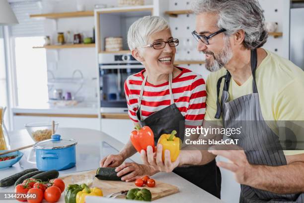 senior couple cooking together at home - healthy older couple stockfoto's en -beelden