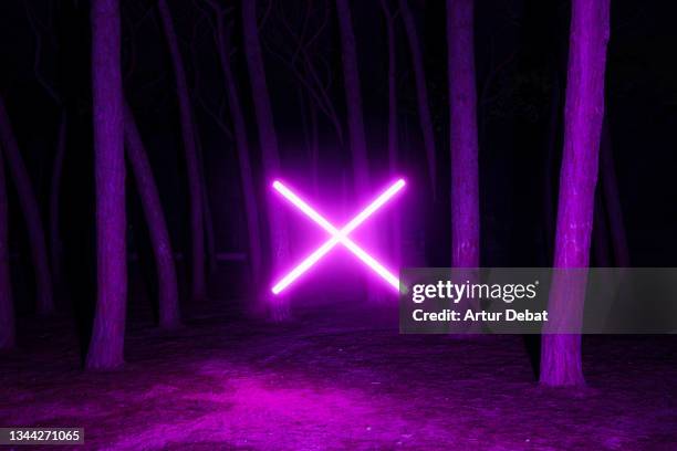 futuristic neon light cross levitating in the dark forest at night. - xes stock pictures, royalty-free photos & images