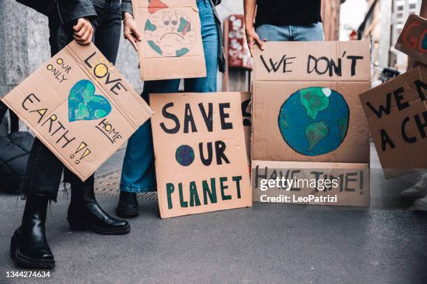 close up on a group of activists holding their handmade protesting messages - climate protest stock pictures, royalty-free photos & images