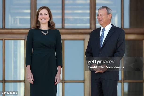 Supreme Court Associate Justice Amy Coney Barrett and Chief Justice John Roberts pause for photographs at the top of the steps of the west side of...