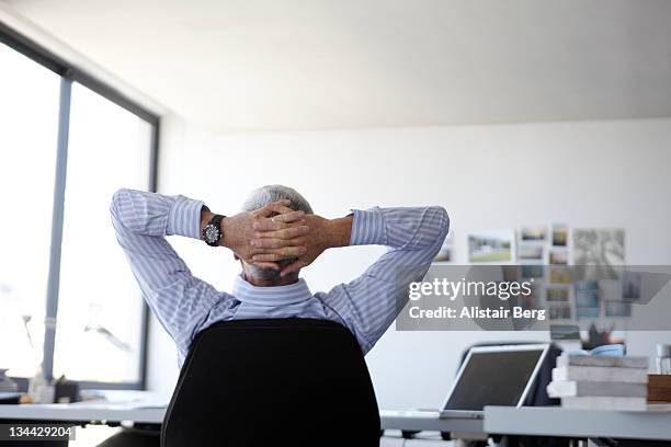 businessman relaxing at his desk - hände hinter dem kopf stock-fotos und bilder