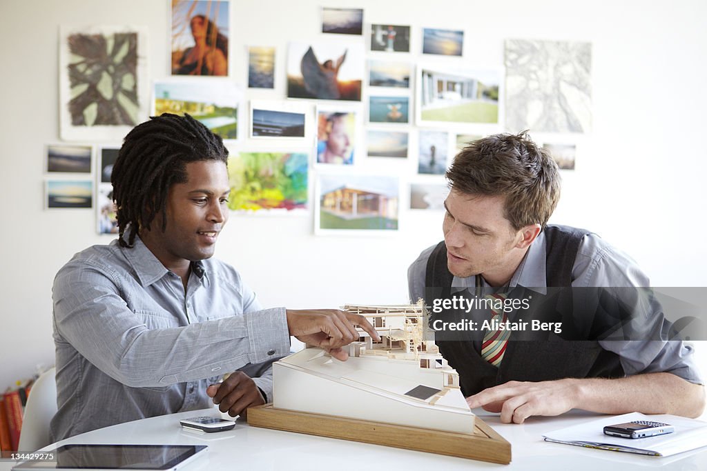 Two architects discussing model of a house