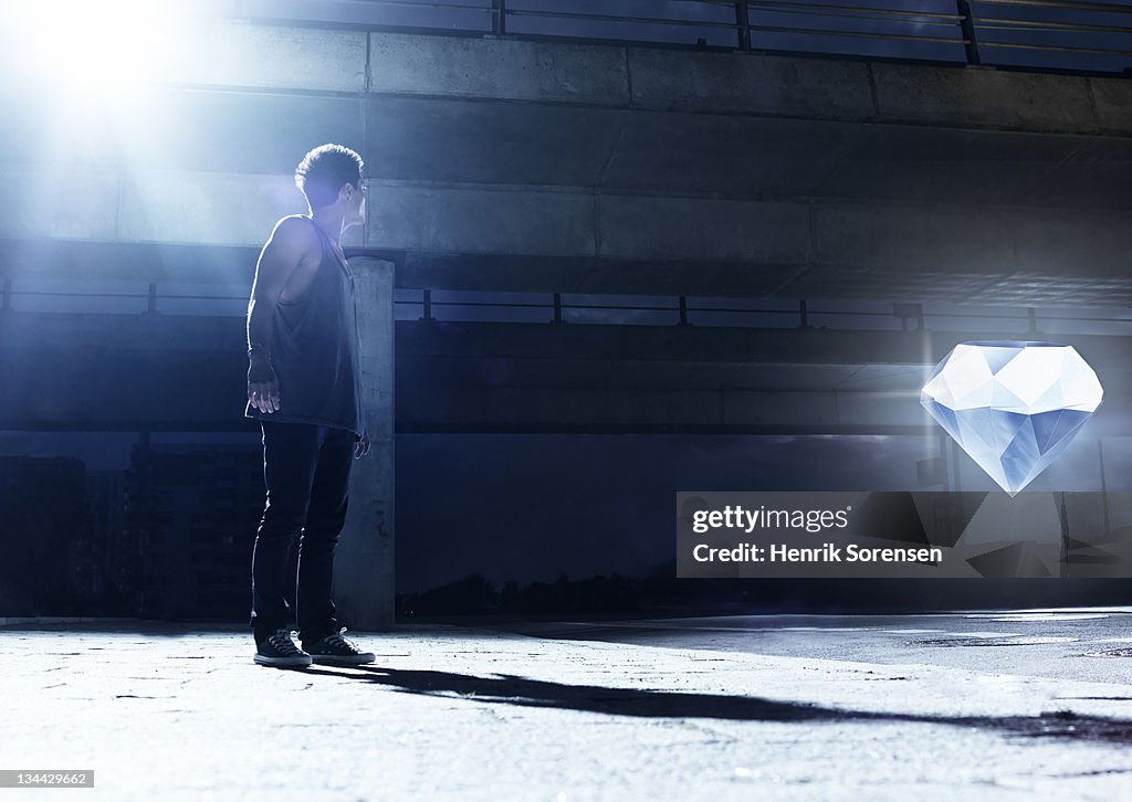 Young man looking at giant glowing diamond