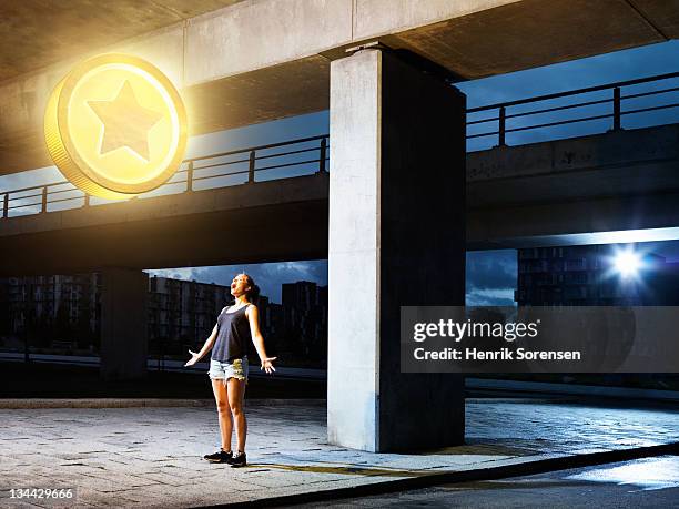 young woman in urban  environment looking at coin - cas awards stock pictures, royalty-free photos & images