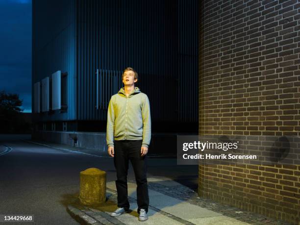 young man in urban environment looking up - ongeloof stockfoto's en -beelden